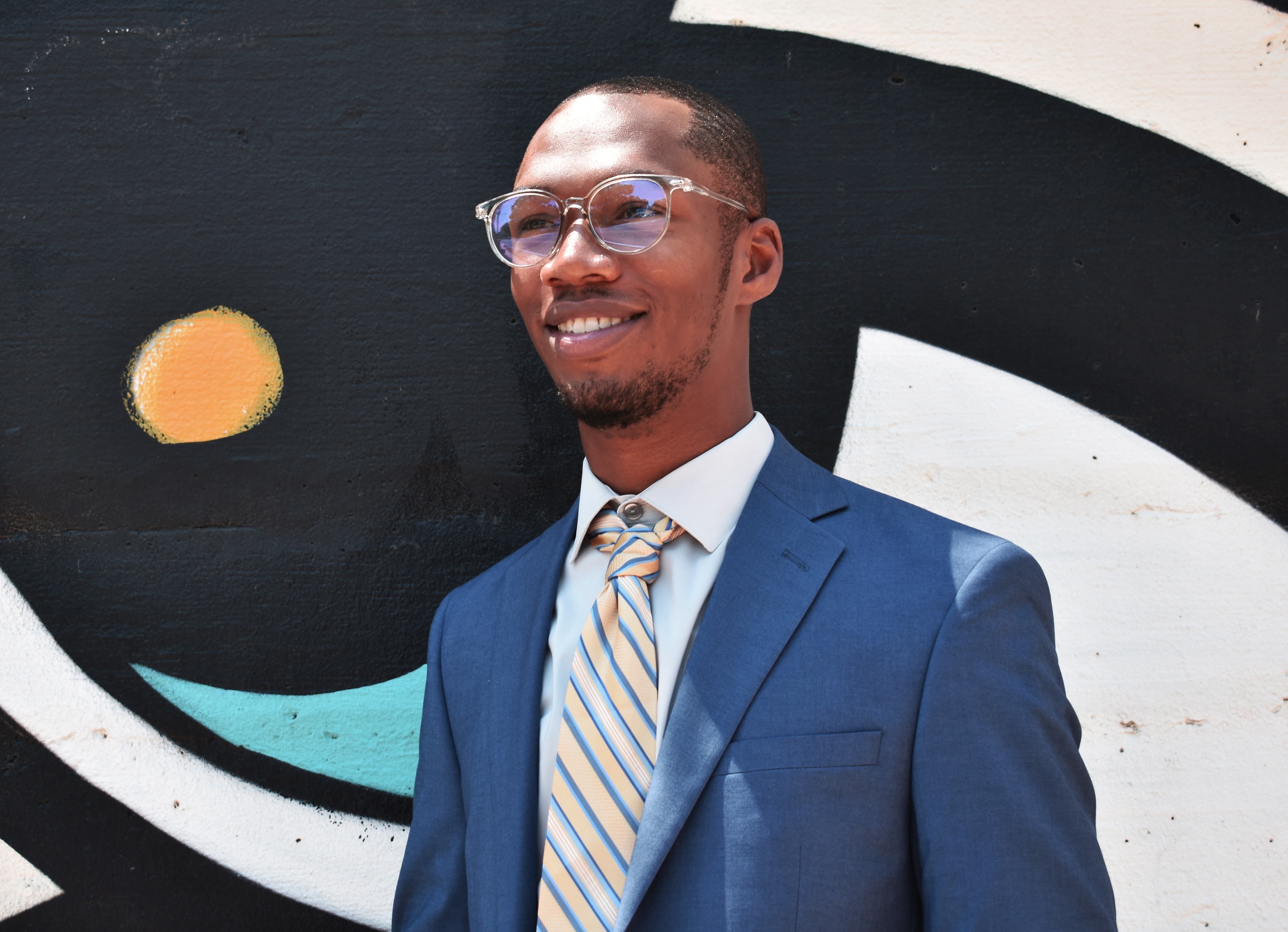 Adam Jacoby Paul smiling in front of mural